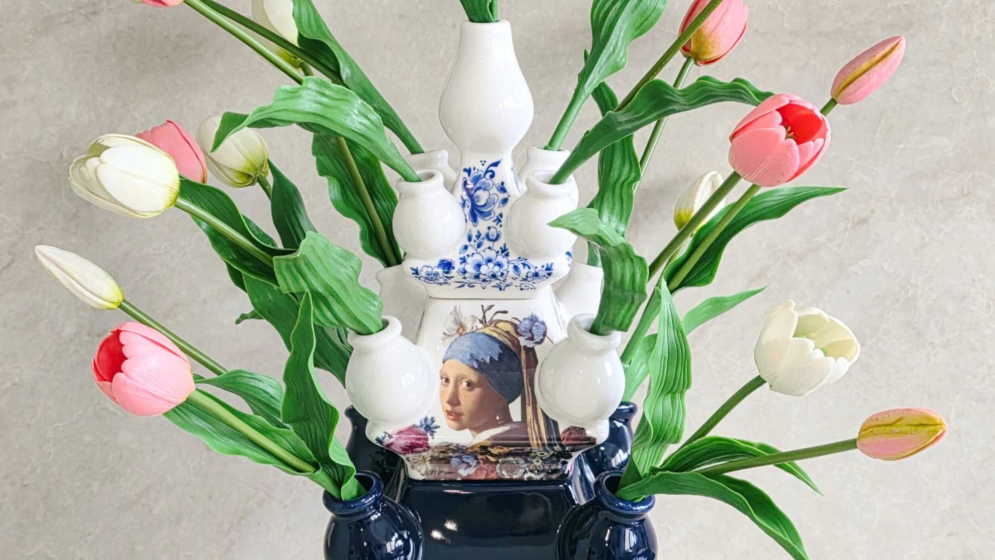 Decorative vase with tulips and a small figurine on a neutral background