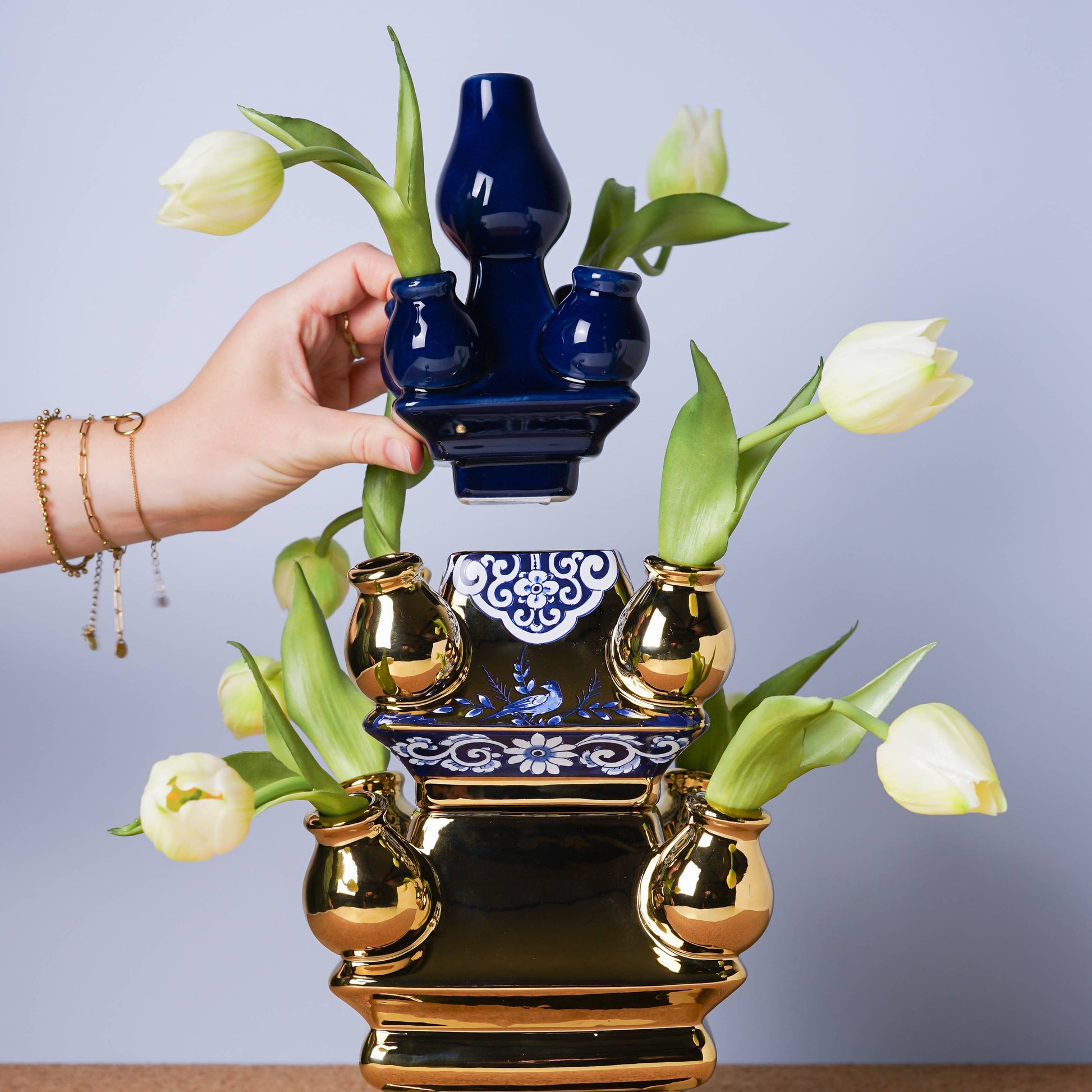 Decorative blue and gold vase with tulips against a plain background