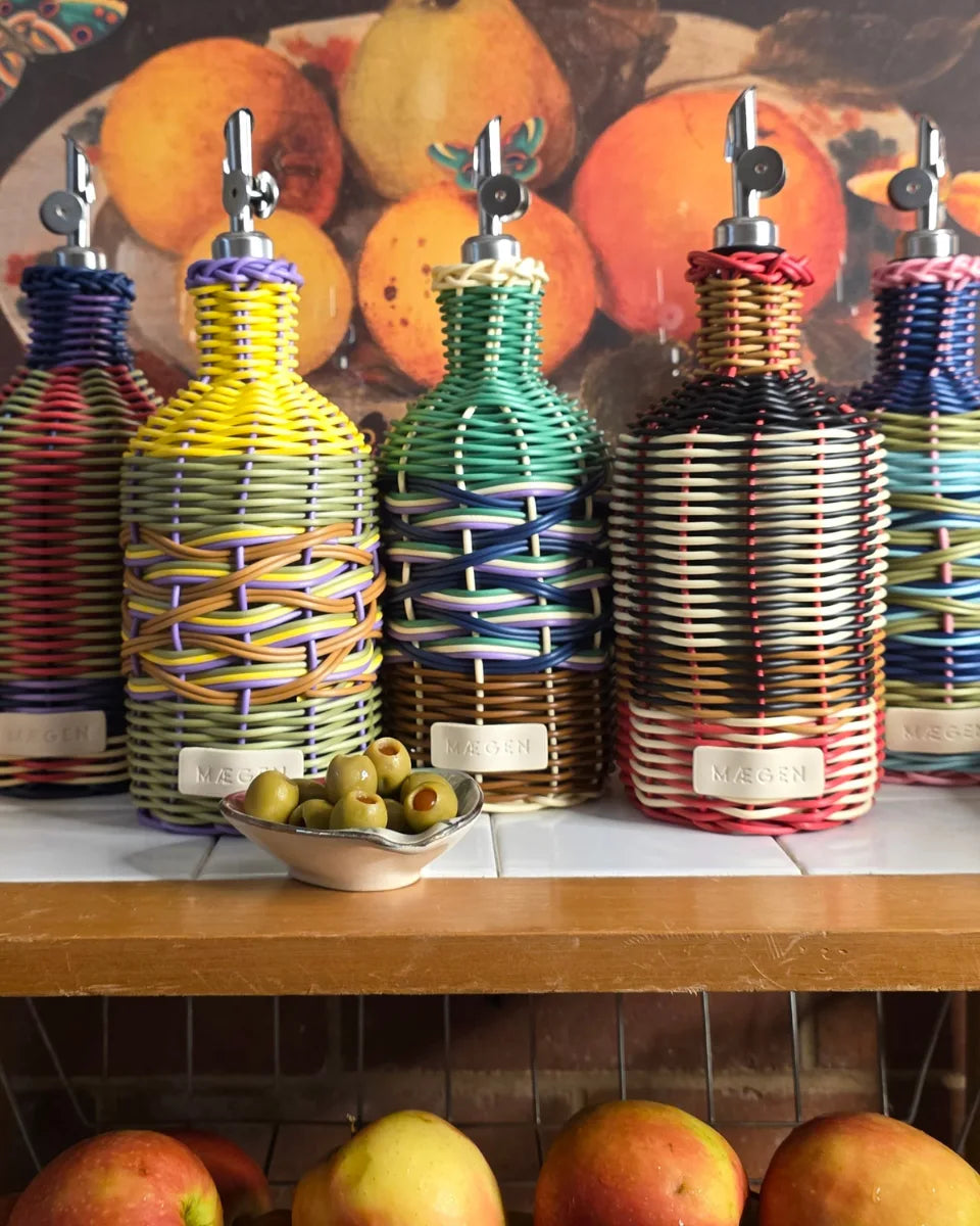 Colourful woven Maegen oil pourers arranged on a kitchen shelf